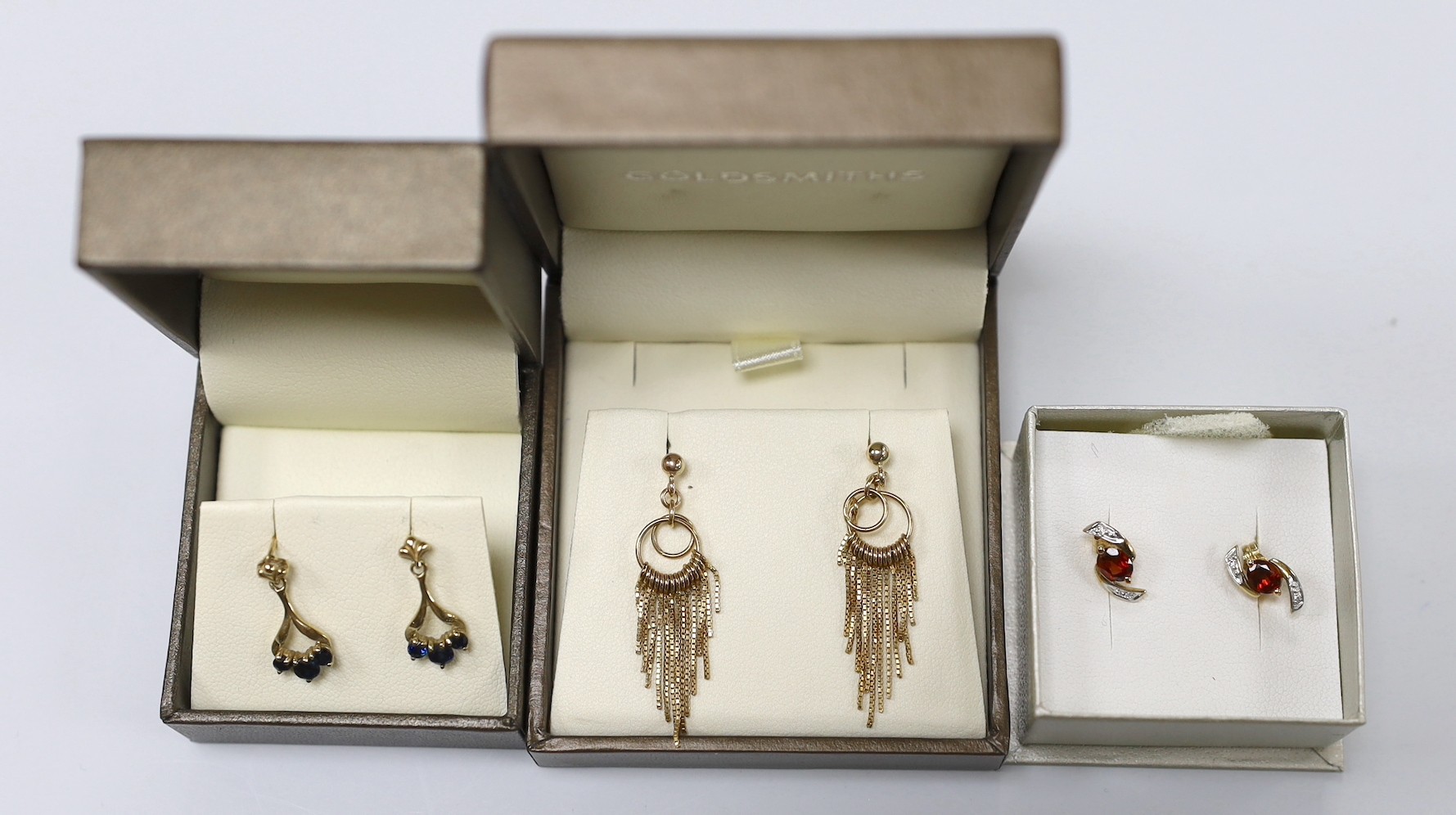 Three assorted modern pairs of yellow metal earrings, including tassel drop, 9ct gold and three stone sapphire (lacking butterflies) and 375 garnet and diamond chip